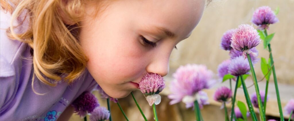Flicka luktar på blomma foto Adobe Stock